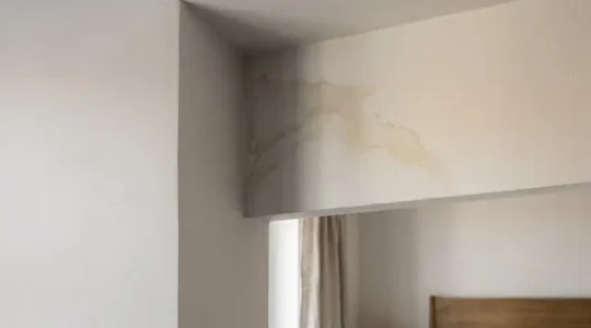Primer plano de una esquina de techo con una mancha de humedad iluminada de forma dramática, evocando la duda entre suciedad y filtración grave
